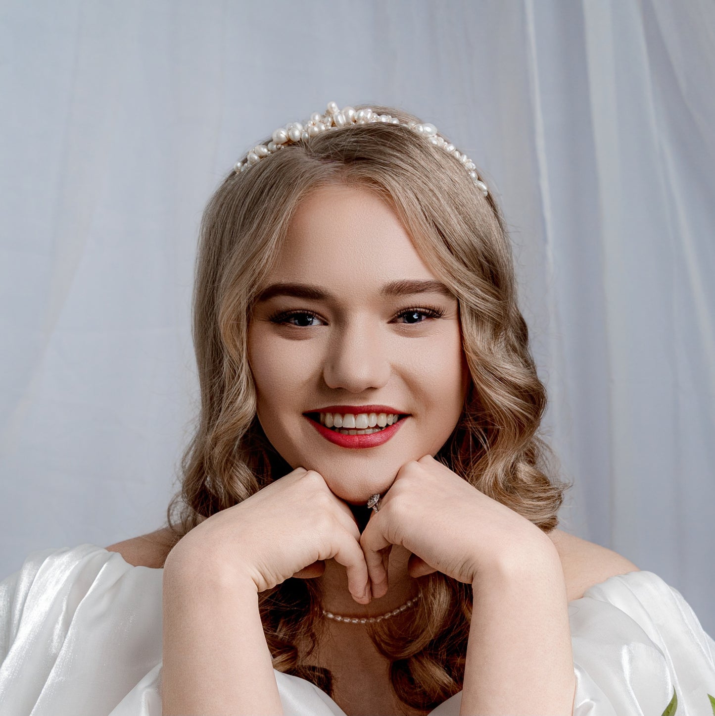 A woman wearing a white bridal gown and cascade tiara adorned with freshwater pearls and pearl necklace.