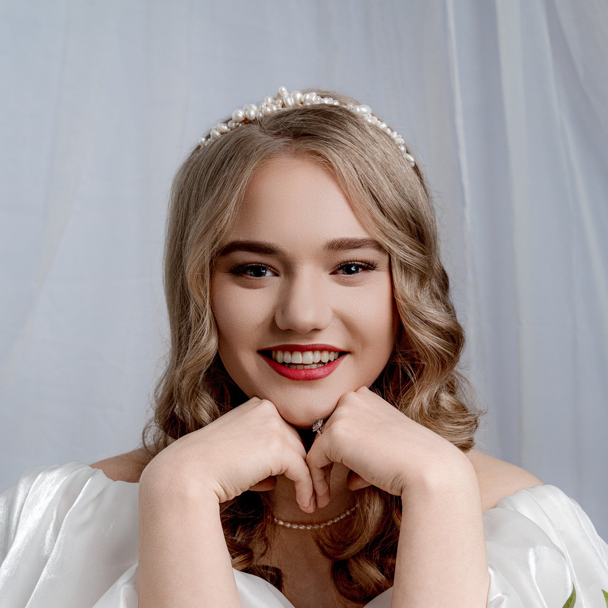 A woman wearing a white bridal gown and cascade tiara adorned with freshwater pearls and pearl necklace.